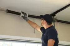 Man lubricating Torsion Spring on a garage door